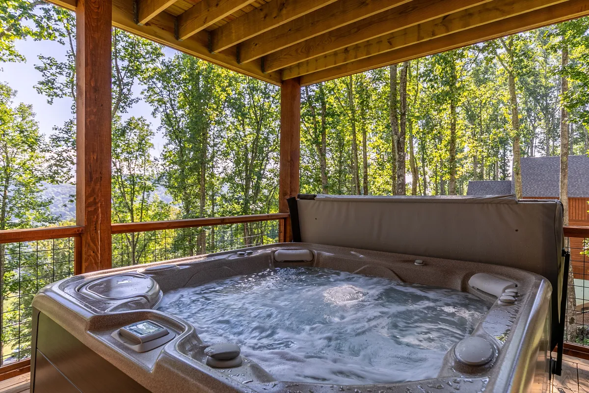 A hot tub set on a deck with a sturdy railing, surrounded by tall trees. The warm, bubbling water invites relaxation, while the natural setting offers privacy and scenic views, especially at sunset or under the stars.